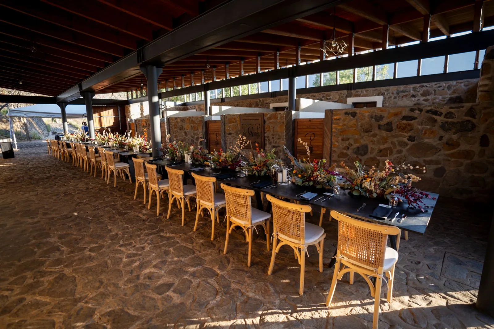 Banquete con mesa larga bajo la terraza de madera, acero y piedra