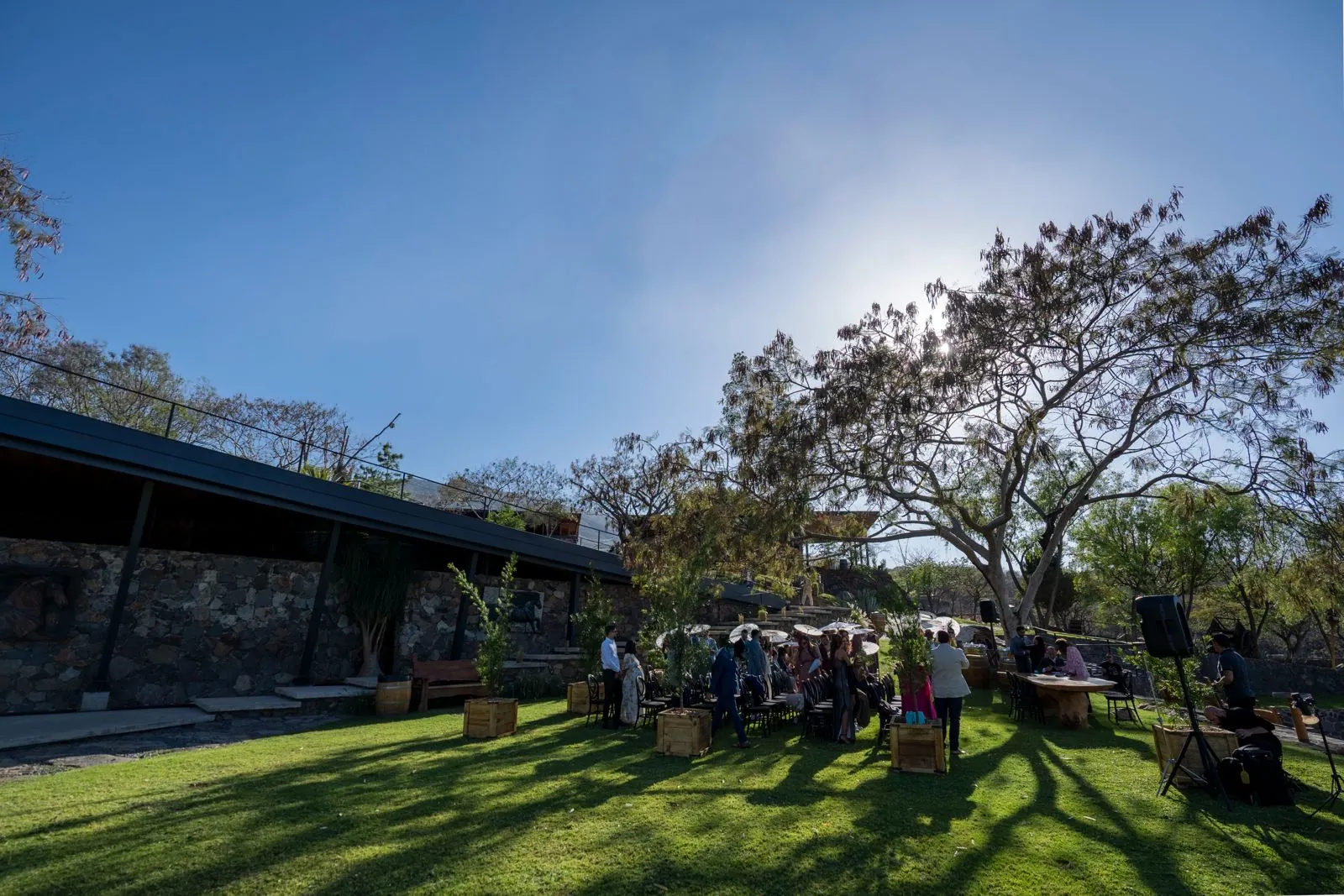 Invitados de una boda en el jardín, junto al muro de piedra