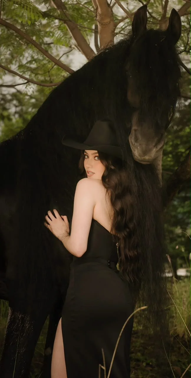 Sesión con sombrero negro bajo los árboles junto a un Friesian